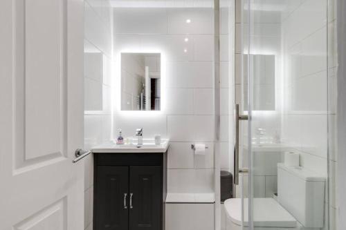 een badkamer met een wastafel, een toilet en een spiegel bij GuestReady - Northern Quarter Urban Escape in Manchester