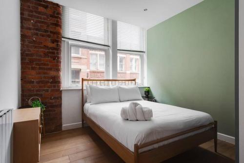 een slaapkamer met een bed met een bakstenen muur bij GuestReady - Northern Quarter Urban Escape in Manchester