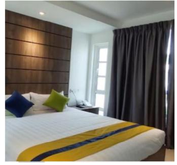 Solesor Kampong Beach Resort في بورت ديكسون: غرفة نوم بسرير كبير وبها وسائد زرقاء وأخضر