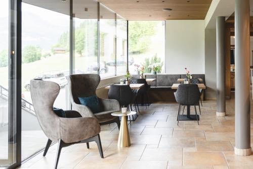un restaurante con sillas, mesas y ventanas en Hotel Lahnerhof en Vipiteno