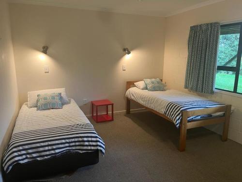 a bedroom with two beds and a window at Aqua Views - Kuratau Holiday Home in Kuratau
