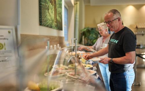 un uomo anziano sta preparando il cibo a un buffet di WaldResort a Weberstedt