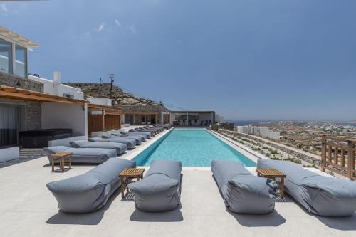 a swimming pool with chaise lounge chairs on a roof at Sunset Hill Suites in Mikonos