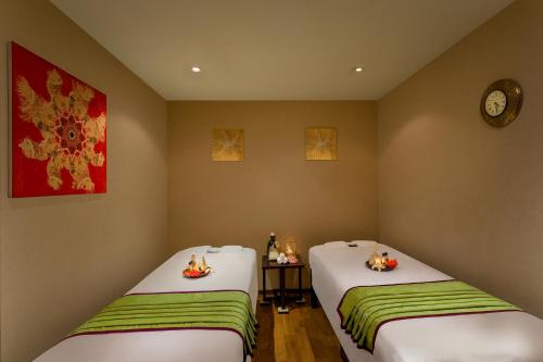 two beds in a room with a clock on the wall at Novotel Ahmedabad in Ahmedabad