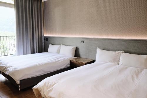 two beds in a hotel room with white sheets at Hoping Mori Hotel in Heping
