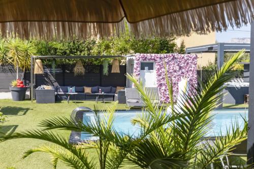 a backyard with a swimming pool with purple flowers at Hôtel Eden Cassis - centre-ville- piscine chauffée, jacuzzi et sauna - parking privé in Cassis