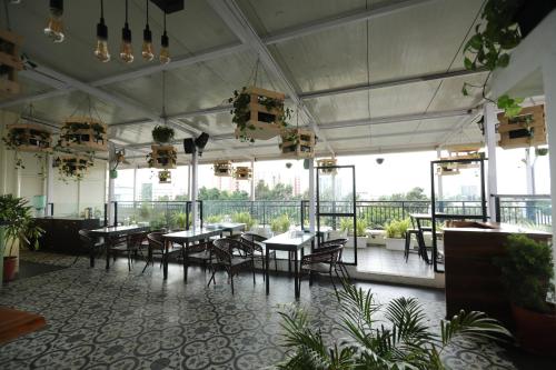 een restaurant met tafels, stoelen en ramen bij Earth Hotels in Bangalore