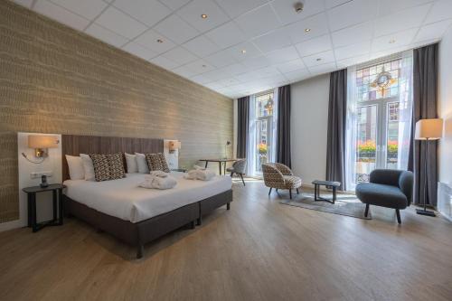 - une chambre avec un grand lit dans une pièce dotée de fenêtres dans l'établissement Hotel Amsterdam De Roode Leeuw, à Amsterdam