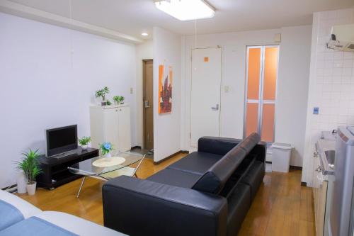 a living room with a black leather couch and a television at ユニオン新大阪 十三駅西中島南方駅 自転車&wifi貸出無料 in Osaka