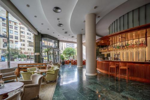 un restaurant avec des tables et des chaises ainsi qu'un bar dans l'établissement Melia Plaza Valencia, à Valence