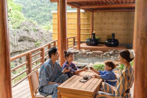a family sitting at a table on a deck at Yoko Onsen Quang Hanh in Cẩm Phả