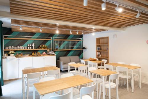 a restaurant with wooden tables and white chairs at Hotel SALEI in Ghigo