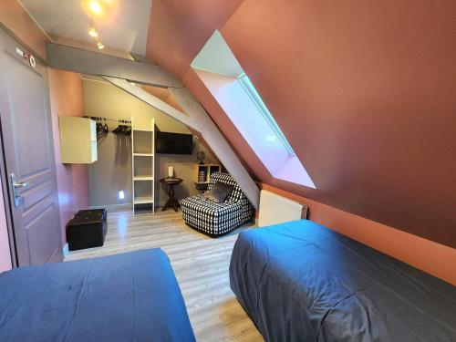 Cette chambre mansardée comprend un lit bleu et un canapé. dans l'établissement Le Domaine du Templier - Maréchal, à Borre