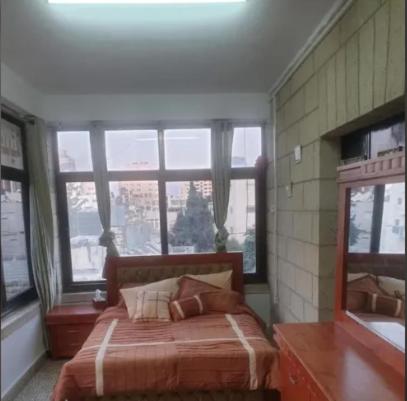 a bedroom with a bed and a large window at Yalla Hostel in Ramallah