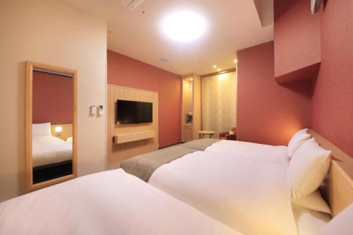 a hotel room with two beds and a television at Richmond Hotel Tokyo Mejiro in Tokyo