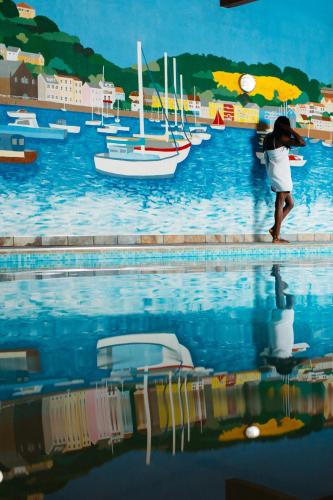 a woman standing next to a pool with boats in the water at Hotel De Normandie in Saint Helier Jersey
