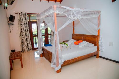 a bedroom with a bed with a canopy at Rockery Villa Ayurveda in Bentota