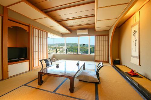 a living room with a table and chairs and a television at Ooedo Onsen Monogatari Ito Hotel New Okabe in Ito