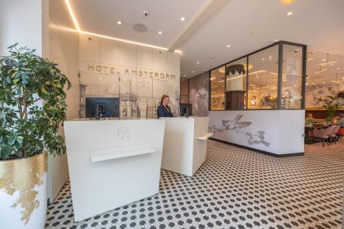 a woman standing at a counter in a store at Hotel Amsterdam De Roode Leeuw in Amsterdam