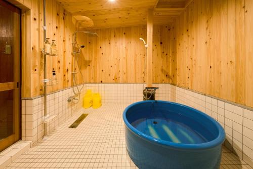 La salle de bains est pourvue d'une grande baignoire bleue et de murs en bois. dans l'établissement 一棟貸切宿 空と家 本棟, à Tadotsu
