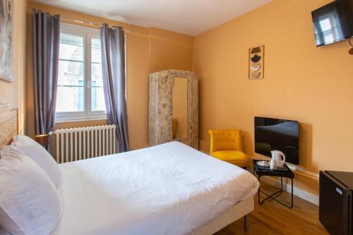 a bedroom with a white bed and a television at L'abbatiale in Corbie