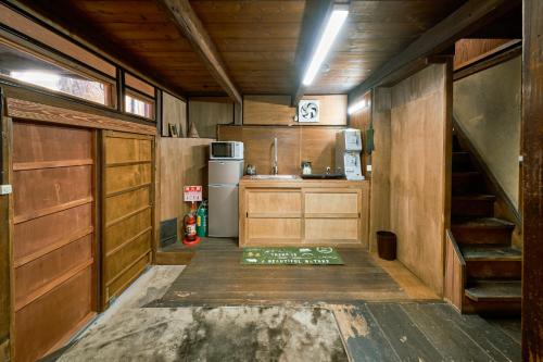 cocina con armarios de madera y nevera en 一棟貸切宿 空と家 本棟 en Tadotsu