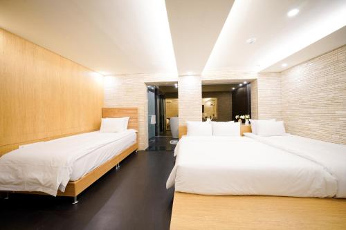 two beds in a hotel room with white sheets at SimpleStay Hotel in Jongno in Seoul