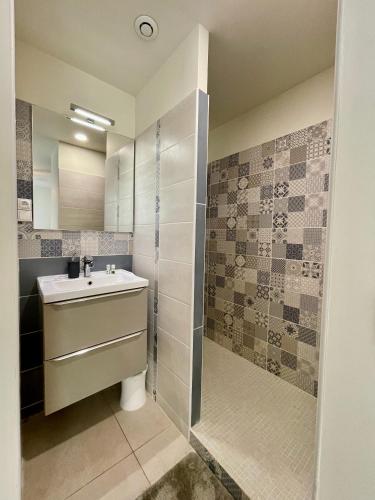 une salle de bain avec un lavabo et une douche dans l'établissement Appartement Souplex Jardin proche autoroute, plages et attractions, Wifi - TV, calme, à Bessan