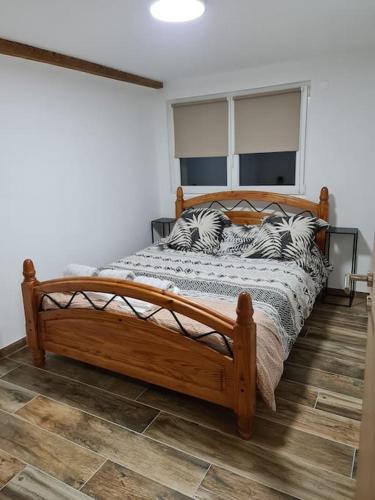 - une chambre avec un lit en bois et des oreillers dans l'établissement Appartement Proche Aéroport Bâle/Mulhouse, à Blotzheim