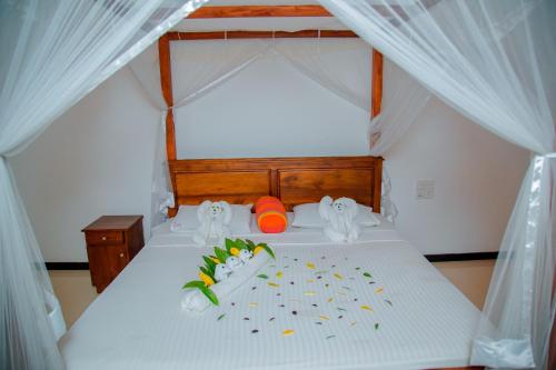 a bedroom with a white bed with white curtains at Rockery Villa Ayurveda in Bentota