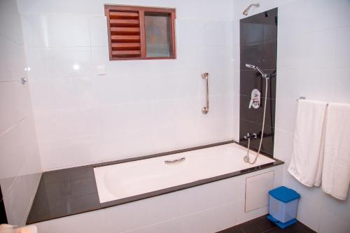 a white bathroom with a tub and a shower at Rockery Villa Ayurveda in Bentota