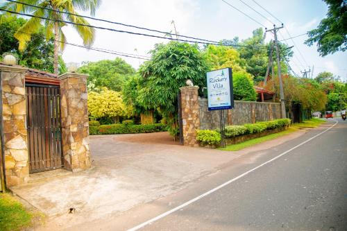 a gate with a sign on the side of a road at Rockery Villa Ayurveda in Bentota