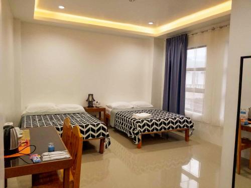 um quarto com duas camas e uma mesa e uma janela em Majestique Hotel Albay Bicol em Guinobatan