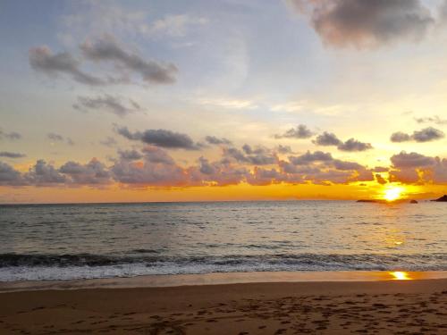 a sunset on the beach with the ocean at Villa Think Of Home in Khao Lak