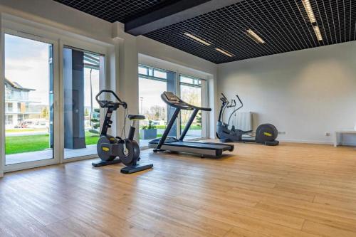 a gym with several exercise bikes in a room with windows at Apartament Bosko przy Jeziorze Żywieckim Laguna Beskidów in Łodygowice