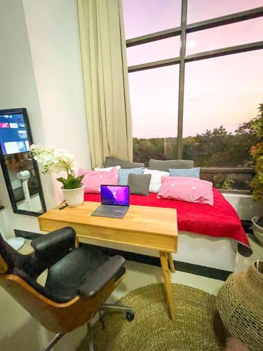 uma secretária com um computador portátil e uma cama num quarto com uma janela em Lovely 1BR Loft in BGC up to 6pax em Manilla