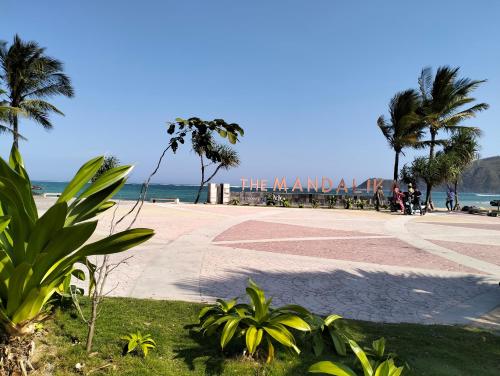 a sandy beach with palm trees and the ocean at T&T Homestay in Kuta Lombok