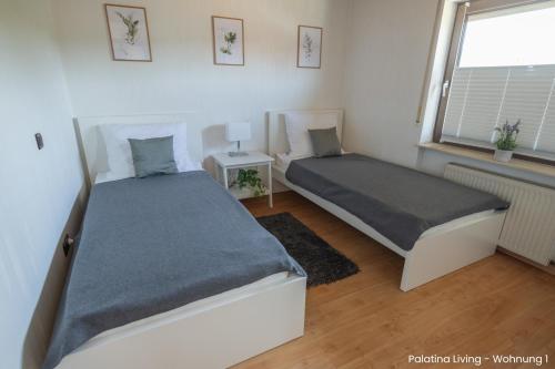 1 dormitorio con 2 camas y ventana en Palatina Living, en Fischbach