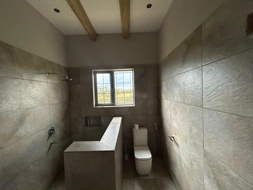 a bathroom with a toilet and a window at Naivasha 4-Bedroom All Ensuite Cottage in Naivasha