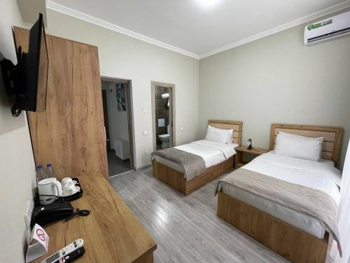 a hotel room with two beds and a flat screen tv at Airport Hotel 24 in Tashkent