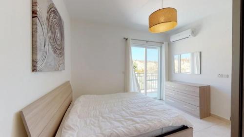 una camera bianca con un letto e una finestra di Calypso Apartment a Marsalforn