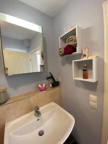 ein Bad mit einem Waschbecken und einem Spiegel in der Unterkunft Ferienwohnung BONHEUR im Kunsthaus 