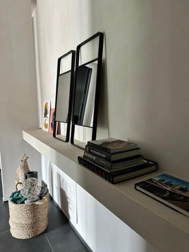 a shelf with two mirrors and a pile of books at Loft al mare Porto San Giorgio in Porto San Giorgio