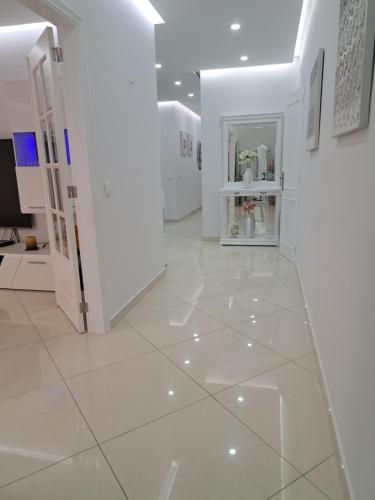 a hallway with white walls and a white tile floor at Zurrinha holidays whit jacuzzi in Quarteira