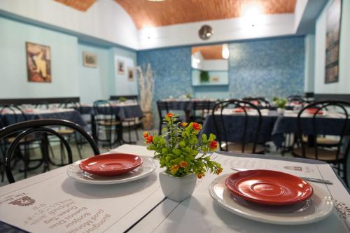 a table with two red plates and a vase with flowers at The Best Hotel in Milan