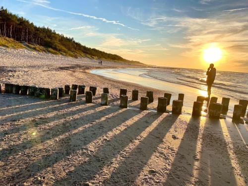 a person standing on the beach at sunset at Apartamenty Czerwone Korale in Chłopy