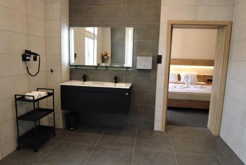 a bathroom with a sink and a mirror and a bed at Apartmány Čechie in Janske Lazne