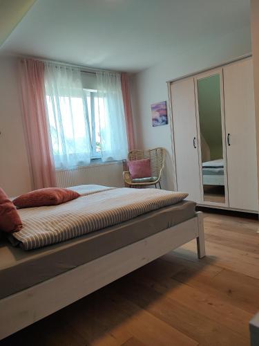 a bedroom with a bed and a chair and a window at Muhrbach in Ottersweier