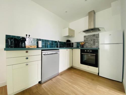 a kitchen with white appliances and a wooden floor at La Capsule de l’Impasse in Limoges