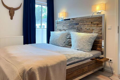 een slaapkamer met een groot bed met een houten hoofdeinde bij Düne 7 Apartment 7A 05 in Zingst